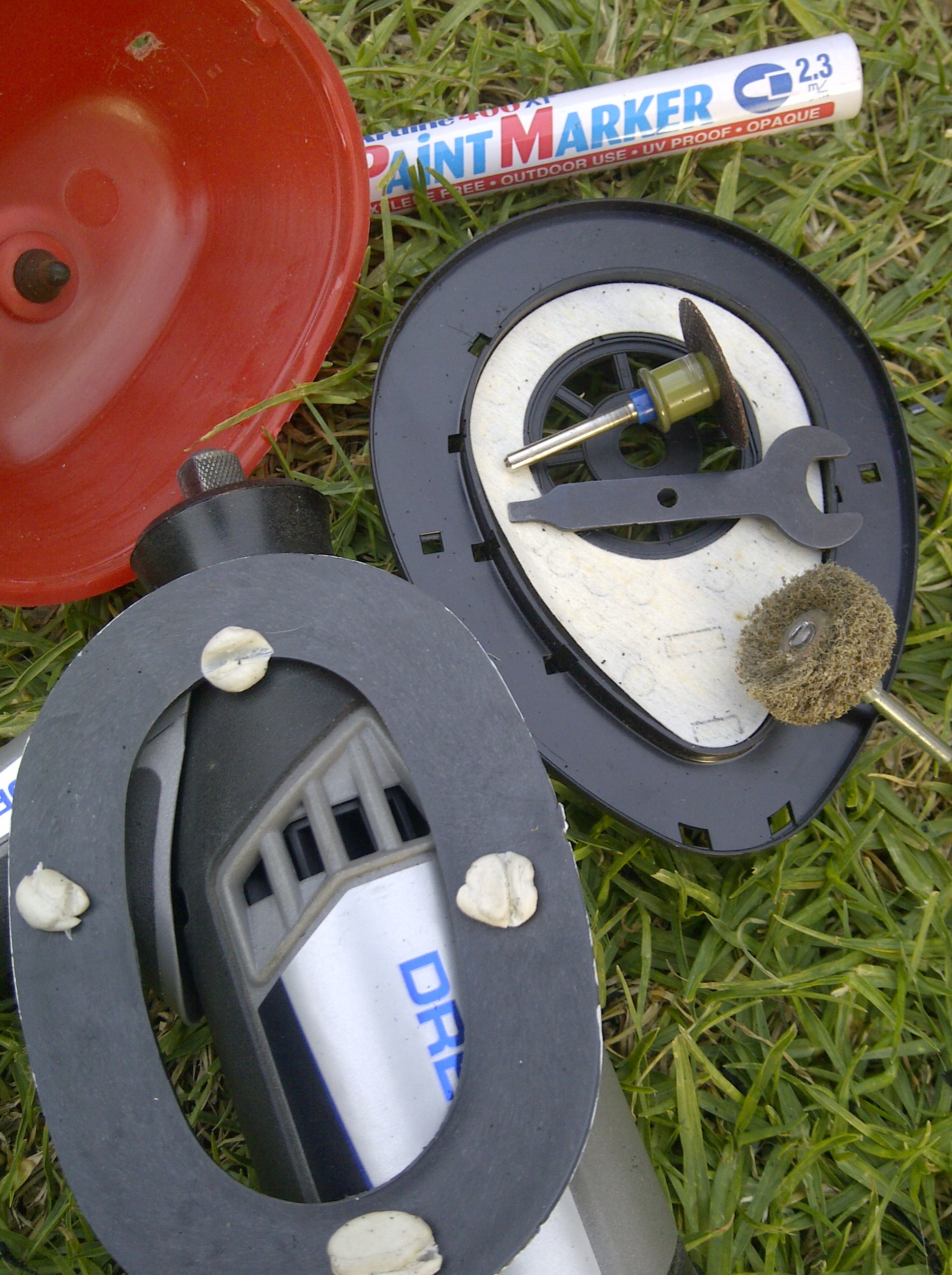 Clockwise from top: The driver mount and the cutting tools, my Dremel and template, the red shell of the ear muffs